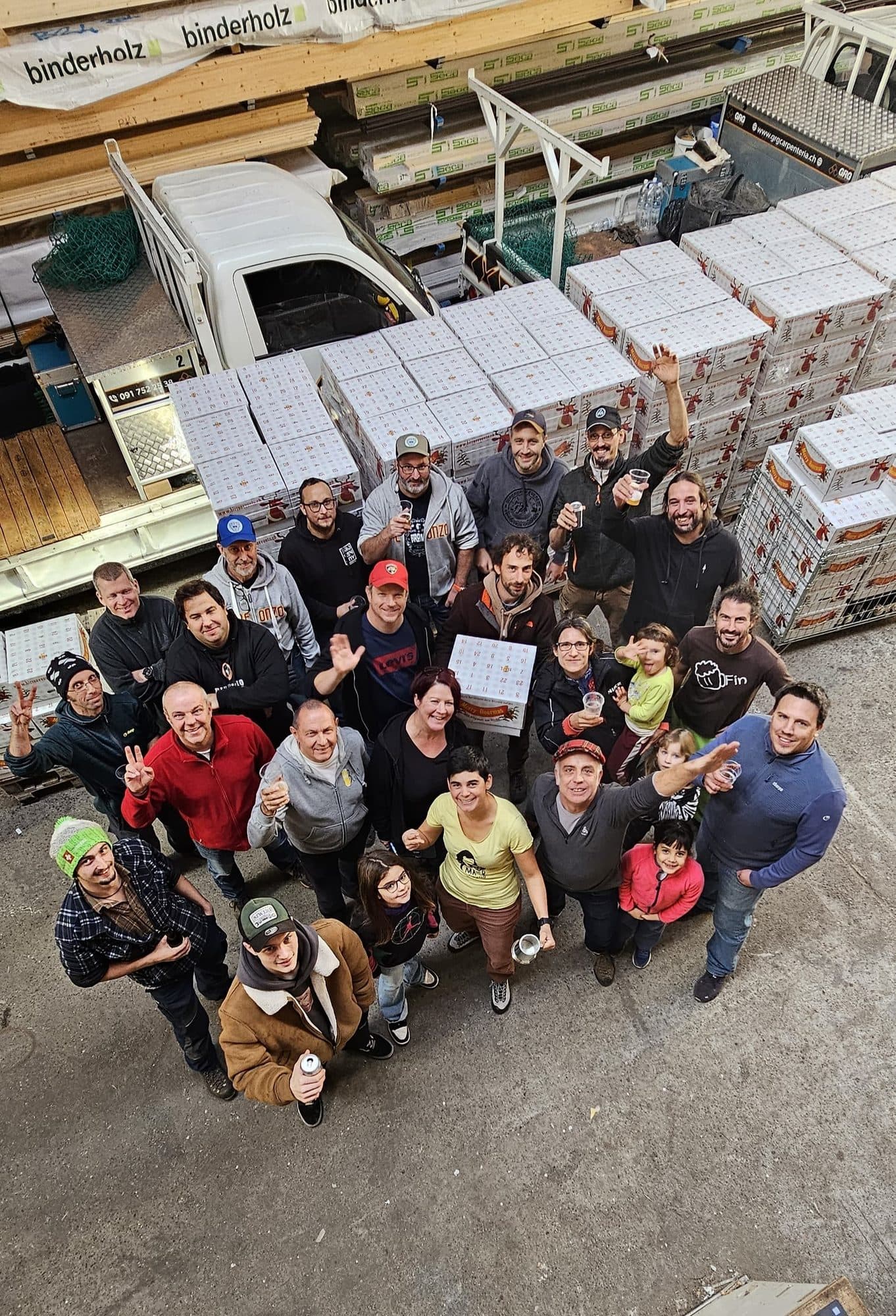 I birrifici di Birreavvento riuniti per la foto di gruppo dell'edizione 2024, davanti ai bancali di calendari appena assemblati.